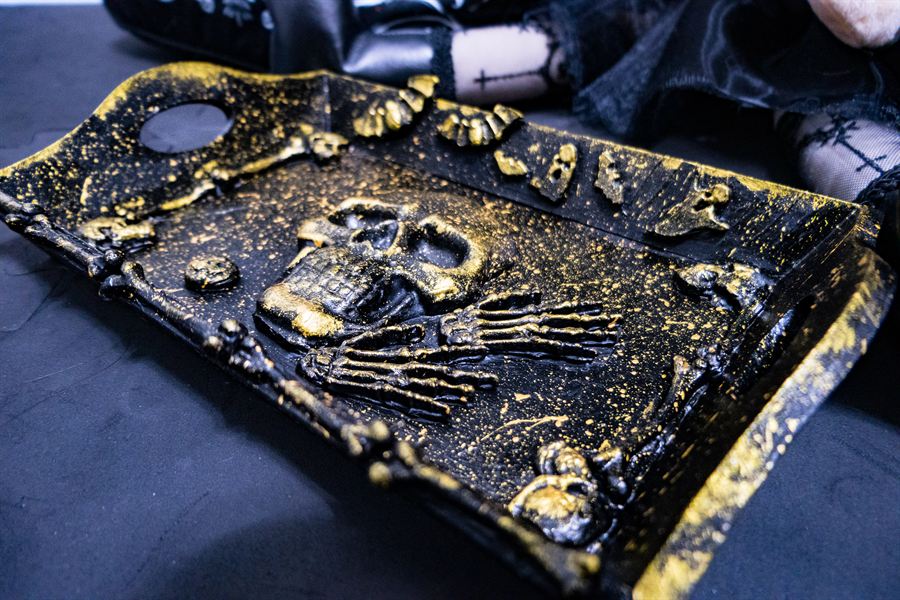Tablett mit Totenkopf- und Skeletthand-Relief, schwarz mit Goldsprenkeln